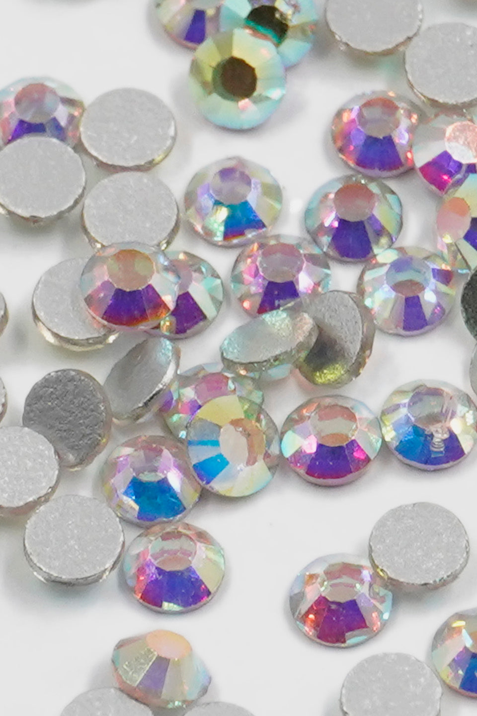 Primo piano ravvicinato degli strass iridescenti. Si distinguono le sfaccettature cristalline che riflettono i colori dell'arcobaleno.