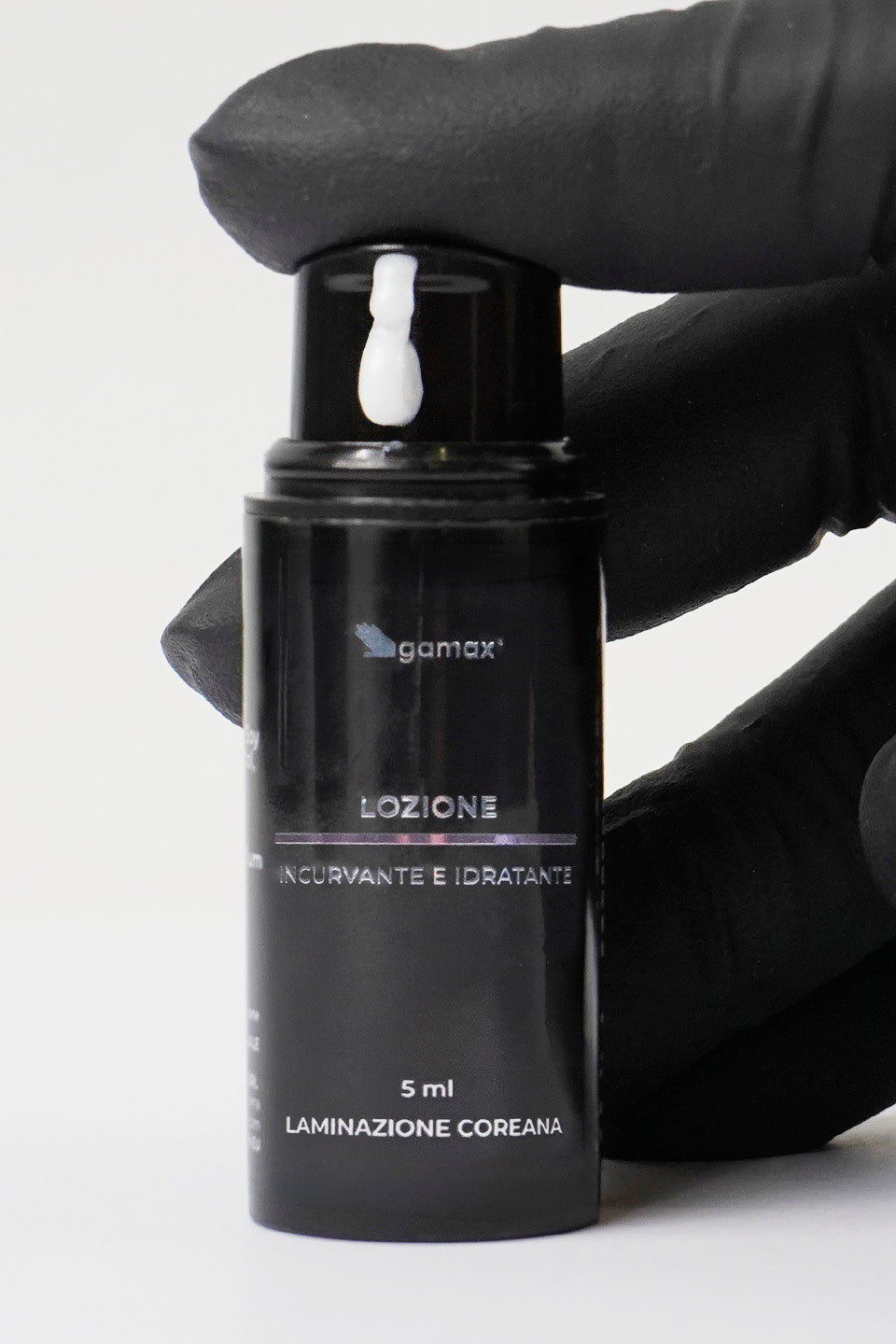 Primo piano del flacone della lozione incurvante ed idratante da 5 ml con mano che schiaccia l'erogatore.