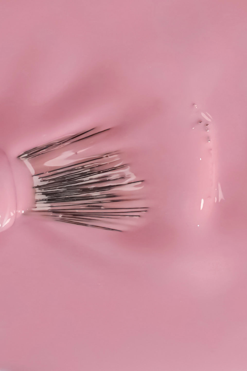 Dettaglio ravvicinato della texture fluida e cremosa dello smalto semipermanente rosa chiaro chiffon. Un pennello a ventaglio è immerso nel colore, mostrando la coprenza omogenea e la finitura lucida del prodotto durante la stesura.