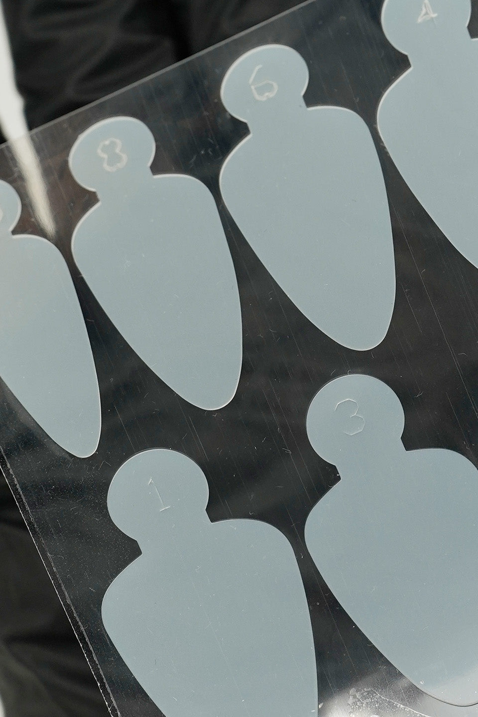 Dettaglio Adesivi in silicone forma j per realizzare unghie dual form in acrygel. fotografati poggiati su un guanto nero per mostrare meglio la forma degli adesivi.
Si leggono alcune misure delle tip.