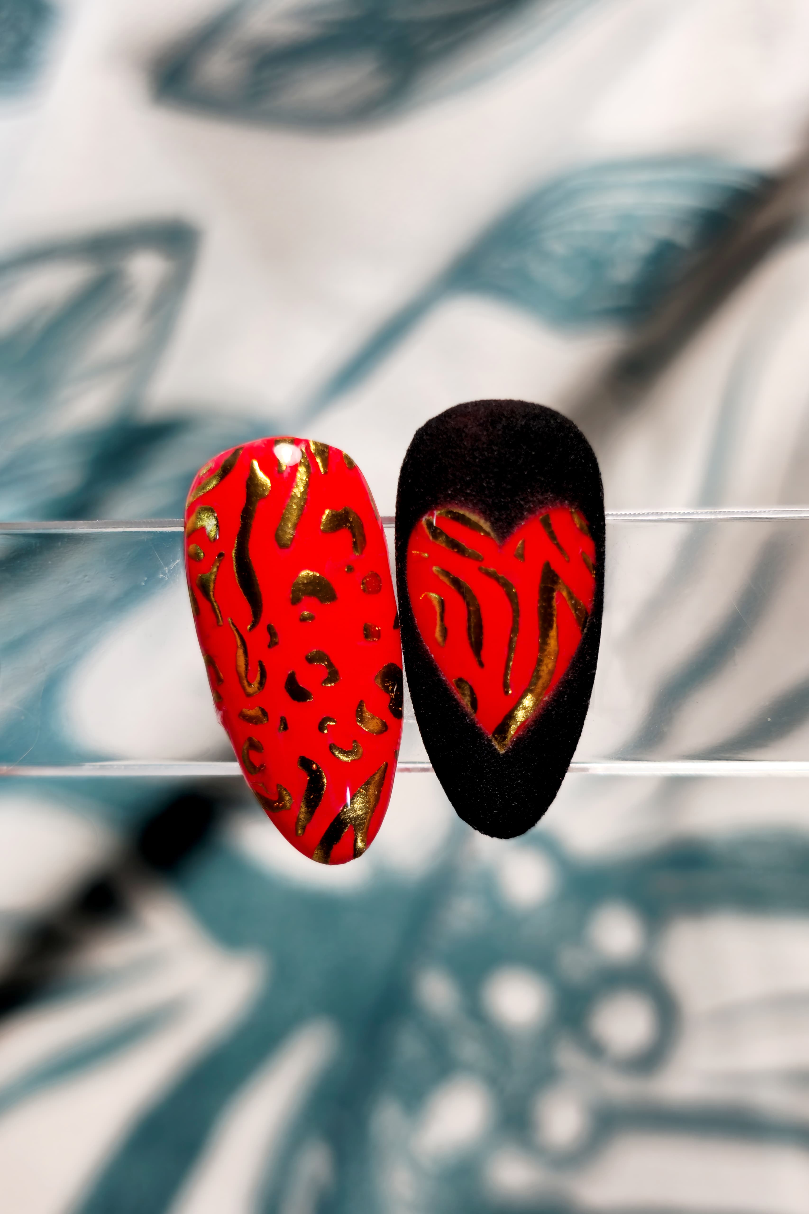 Nail Art su tip realizzata con adesivi unghie stile leopardato oro. Base Rossa, pattern leopardato oro. Sulla tip di destra è stato applicato un contorno nero che va a formare un cuore con la base dell'unghia: rosso e leopardato oro.