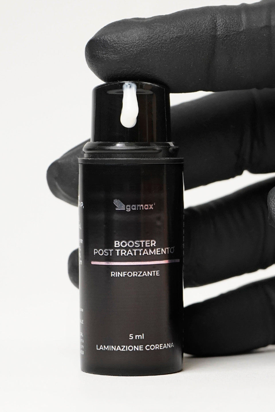 Booster post trattamento rinforzante, guanto nero che preme sul dosatore facendo fuoriuscire una piccola dose di prodotto