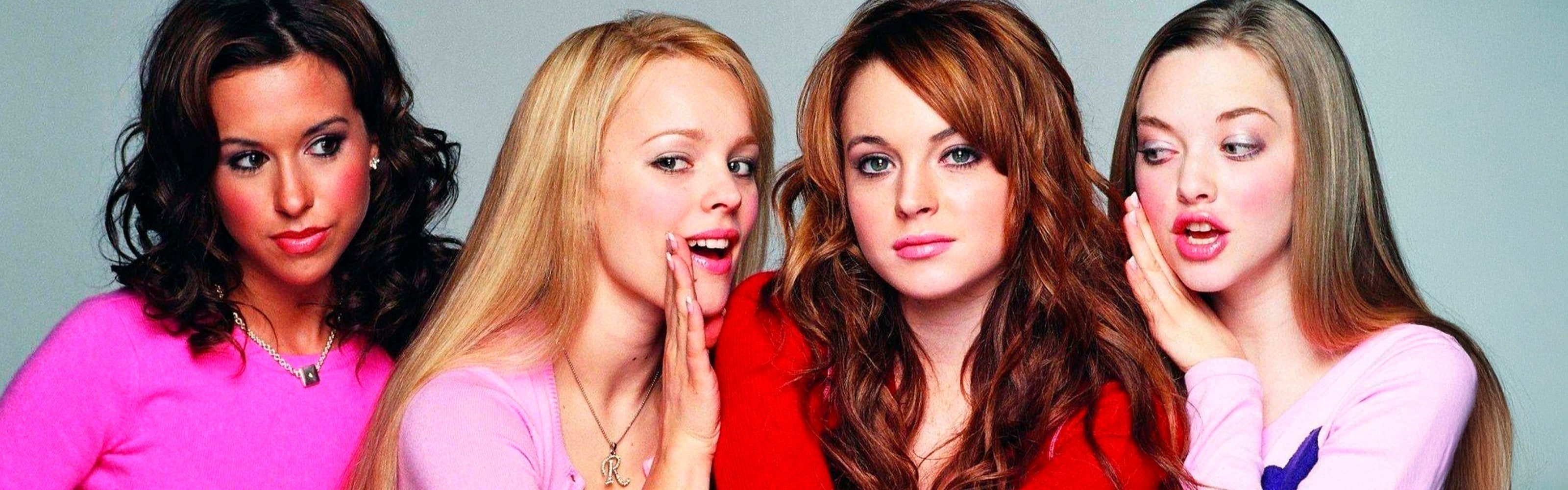 Scena estratta dal film "Mean Girls": quattro ragazze vestite in pieno look e trucco anni 2000 guardano in camera mentre si parlano all'orecchio e interagiscono tra loro