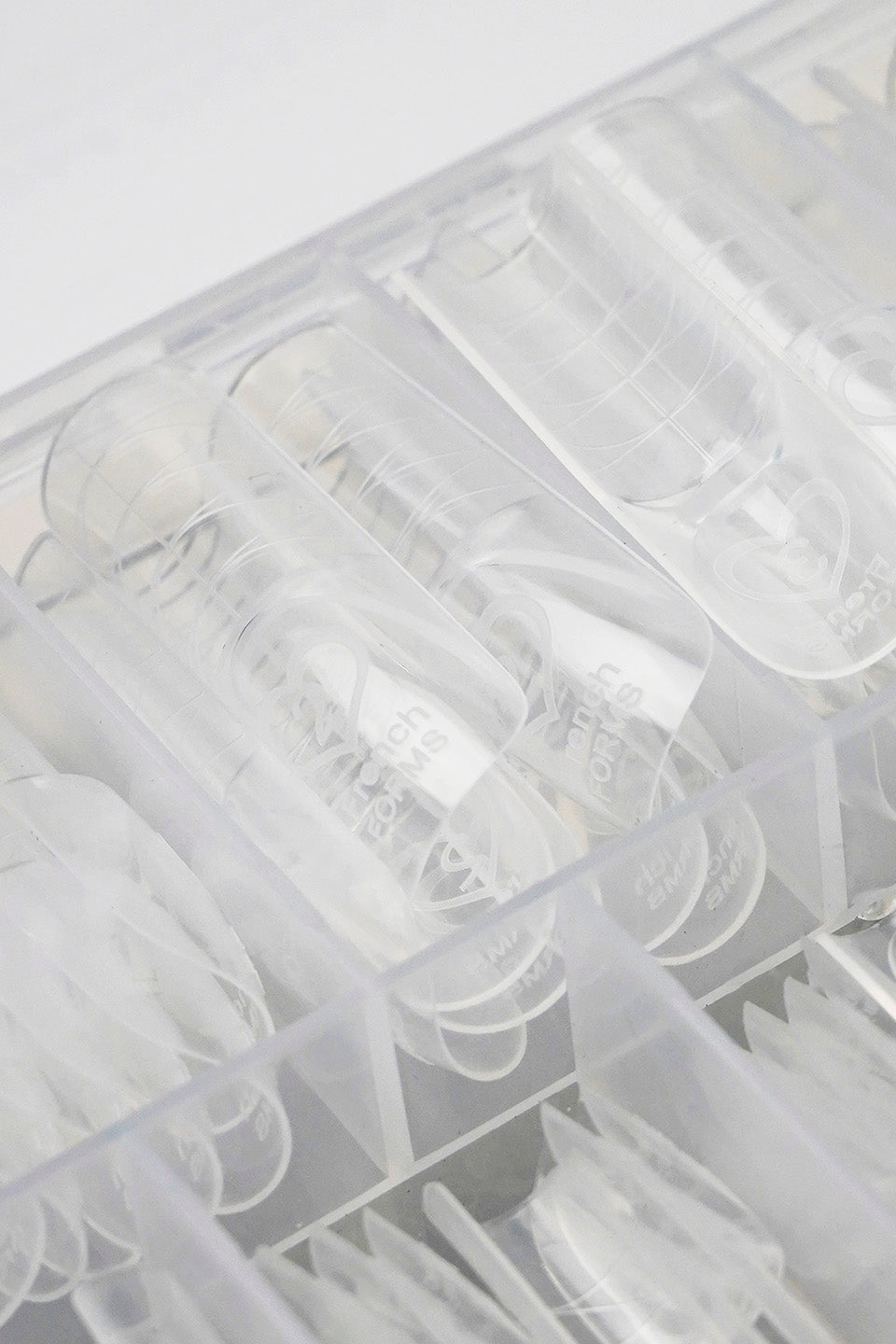 Scatola organizer in plastica trasparente aperta che mostra diverse misure di Dual Form trasparenti per la ricostruzione unghie, ordinate nei vari scomparti.