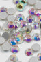 Primo piano ravvicinato degli strass iridescenti. Si distinguono le sfaccettature cristalline che riflettono i colori dell'arcobaleno.
