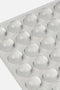Inquadratura ravvicinata e angolata di un foglio con bolle adesive in silicone paracolpi trasparenti per tastiera pc, che mette in risalto la loro forma a cupola tridimensionale.