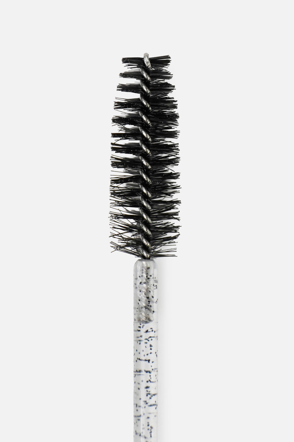 Primo piano verticale della testina di uno scovolino monouso per ciglia con setole nere fitte disposte a spirale intorno a un'anima in metallo. Il manico sottostante è in plastica trasparente con glitter scuri, il tutto su sfondo bianco