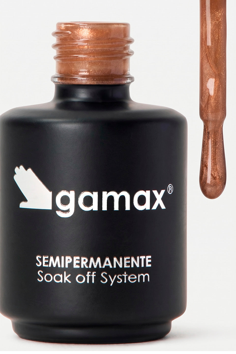 Primo piano di un flacone di smalto nero opaco del marchio Gamax. Sul flacone compare la scritta bianca "SEMIPERMANENTE Soak off System". Il tappo è rimosso e mostra un pennellino sollevato da cui cola una goccia di smalto color bronzo metallizzato e glitterato.