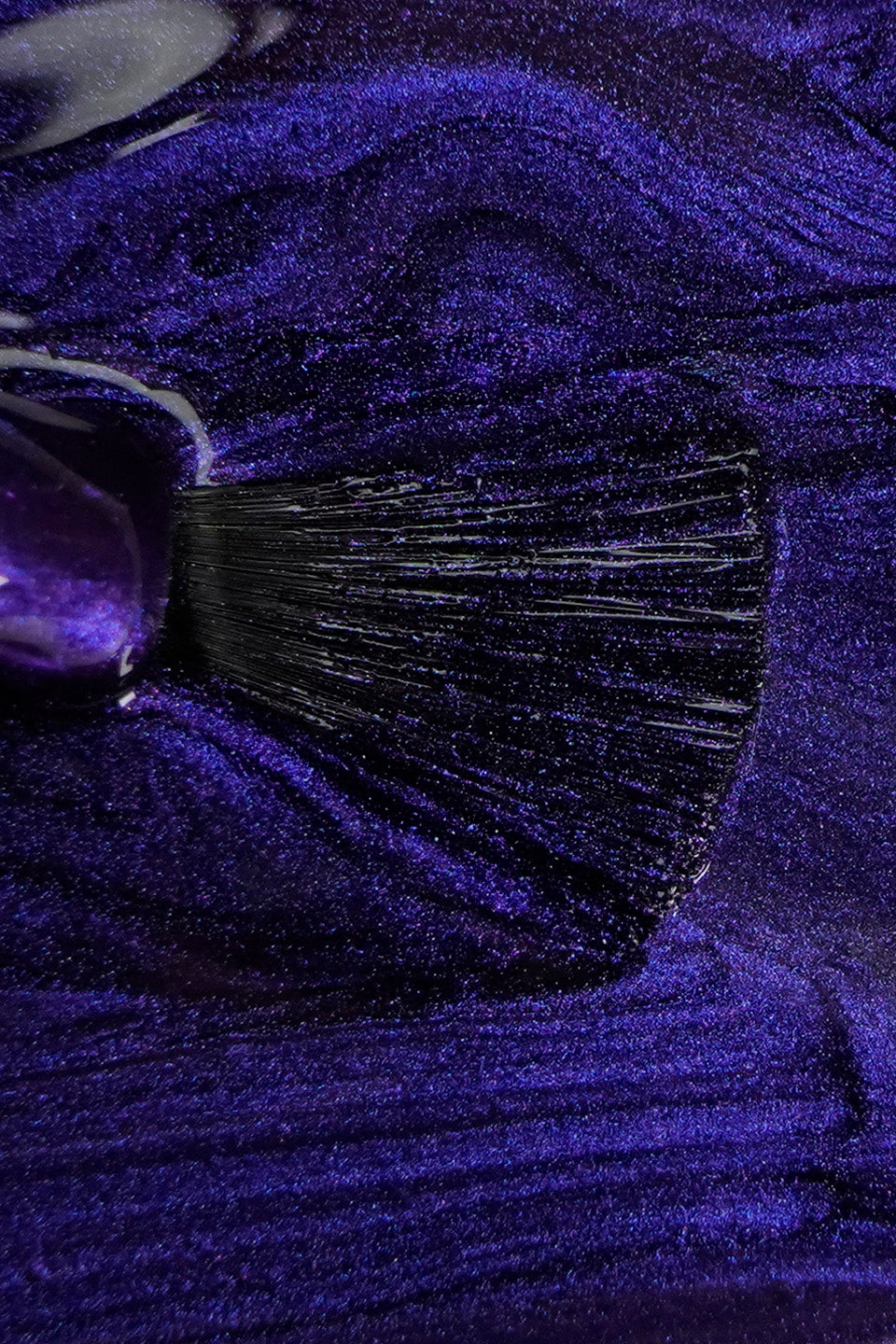 Primo piano del flacone nero opaco Gamax "SEMIPERMANENTE Soak off System". L'applicatore sollevato mostra una goccia di smalto di colore chiaramente indaco con riflessi magnetici argentati e brillanti. Il collo del flacone rivela la densità del prodotto e la sua finitura luminosa e metallizzato