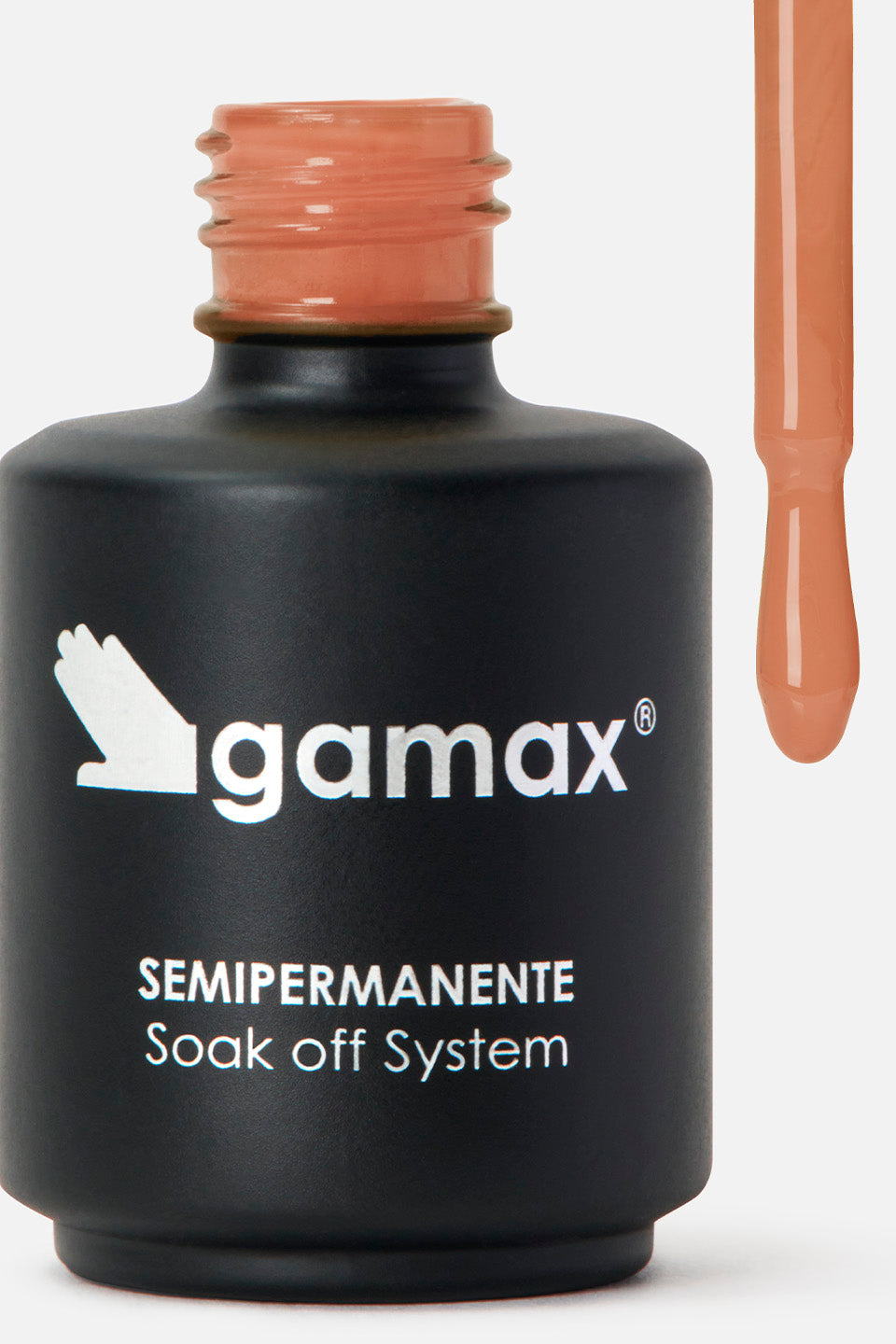 Primo piano di un flacone di smalto nero opaco del marchio Gamax, con scritte bianche che riportano "SEMIPERMANENTE Soak off System". Sulla destra, l'applicatore è sollevato e mostra l'estremità del pennellino coperta da uno smalto fluido di colore pesca pastello, con una goccia pronta a scendere.