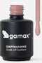 Primo piano di un flacone di smalto nero opaco del marchio Gamax, con scritte bianche che riportano "SEMIPERMANENTE Soak off System". Sulla destra, l'applicatore è sollevato e mostra l'estremità del pennellino coperta da uno smalto fluido di colore rosa pastello, con una goccia pronta a scendere.