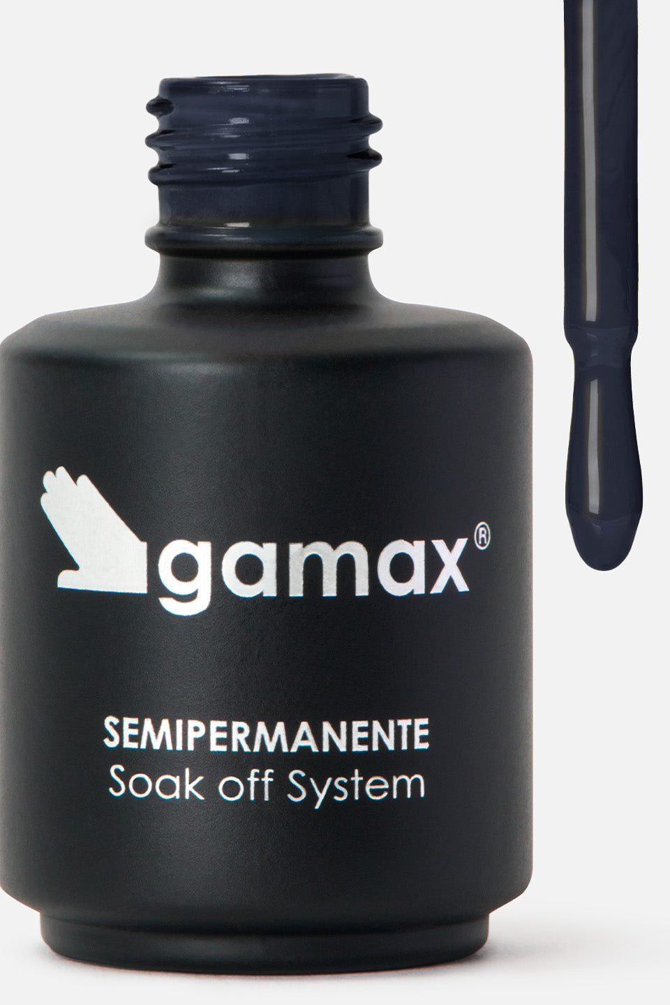 Una boccetta di smalto semipermanente di colore nero opaco con etichetta e logo Gamax. La boccetta è aperta, e accanto ad essa è visibile l'applicatore con l'asta e la goccia di smalto di colore blu scuro, quasi nero, che sta per cadere. L'etichetta bianca sulla boccetta riporta il logo Gamax e le scritte 'SEMIPERMANENTE' e 'Soak off System'.