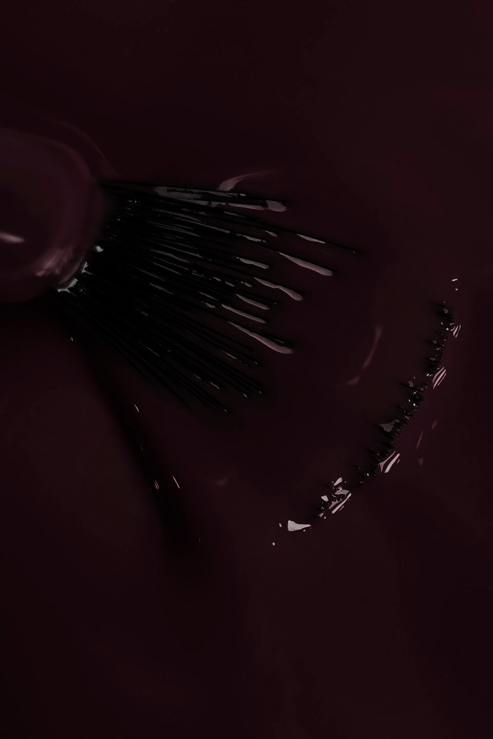 Dettaglio ravvicinato della texture fluida dello smalto semipermanente amarena scuro incanto. Un pennello a ventaglio è immerso nel colore, mostrando la coprenza omogenea e la finitura lucida del prodotto durante la stesura.