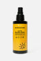 Flacone di latte solare spray su sfondo neutro. Flacone in plastica nera con etichetta gialla e scritte nere. Senza tappo con spruzzino spray visibile. 