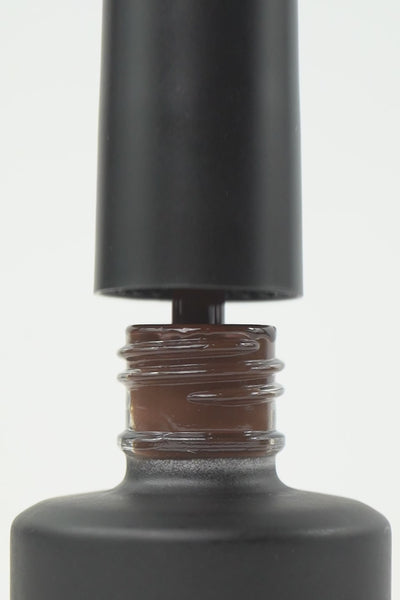 Video macro dello smalto semipermanente Ambra color marrone scuro. Mostra il pennellino che preleva una goccia densa e lucida dal flacone, l'applicazione fluida su unghia naturale e il finish finale ultra brillante, coprente e liscio effetto vetro