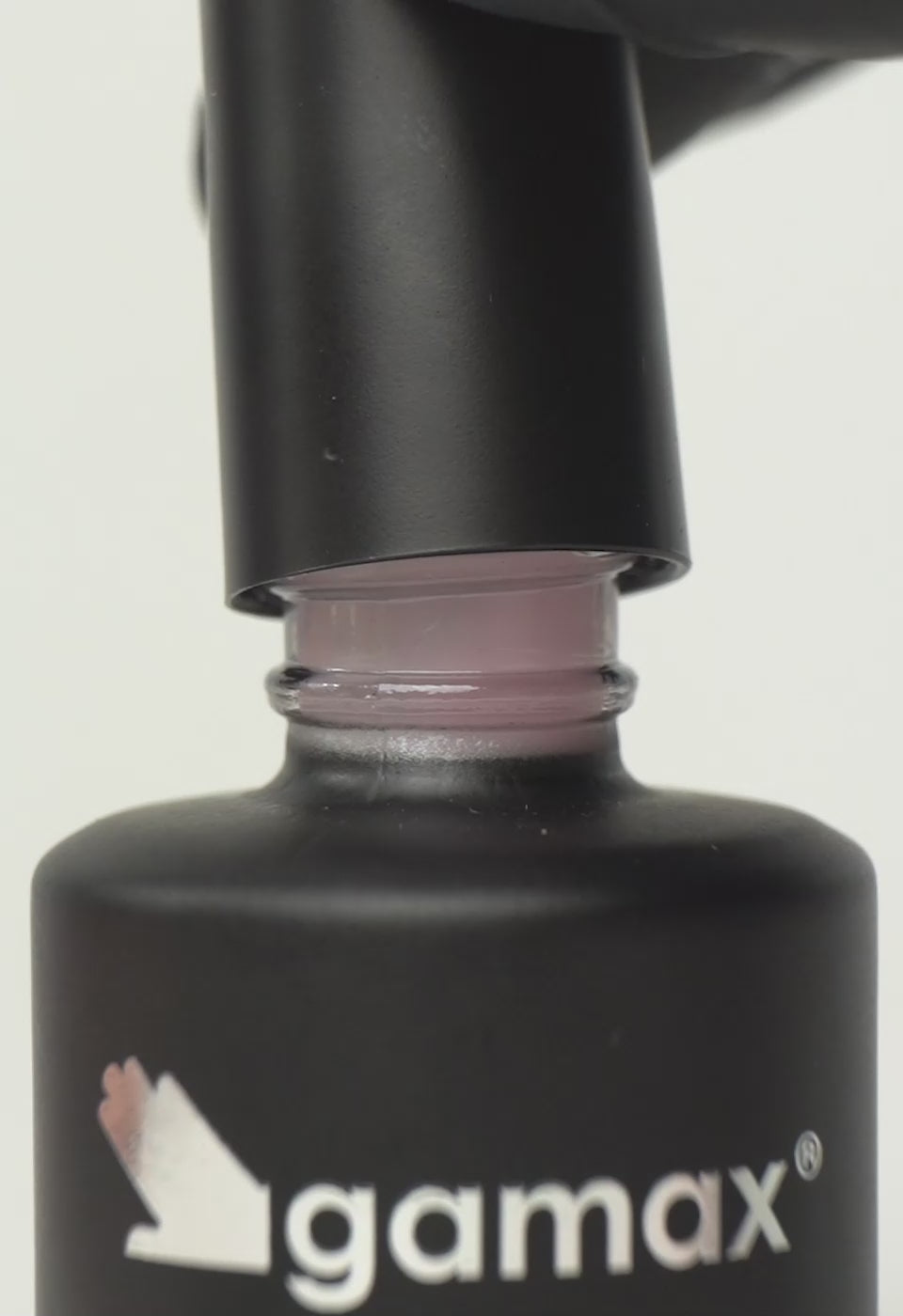 Si succedono diversi frame che mostrano il flacone nero contenente il top coat rosa latte di Gamax, la texture dello smalto e infine un'unghia su cui viene applicato il prodotto