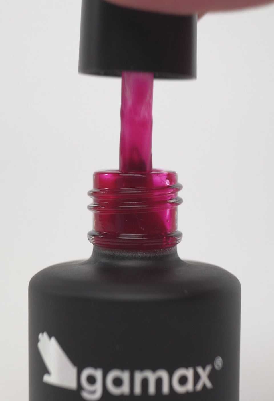 Video ravvicinato dell'applicazione di uno smalto semipermanente di colore rosso magenta intenso. Il video mostra il pennello che preleva il prodotto dal flacone, la stesura fluida e uniforme sull'unghia del pollice e il finish lucido finale.