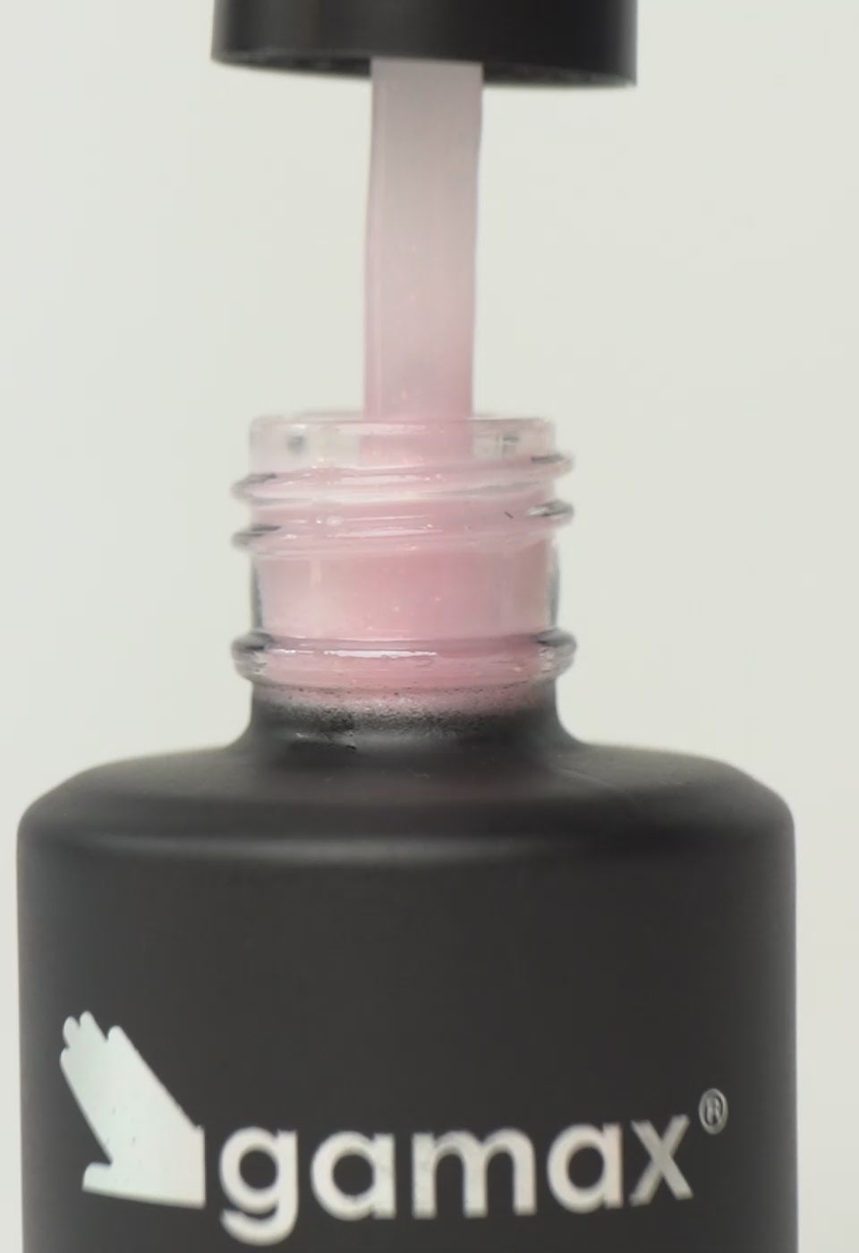 Si succedono diversi frame che mostrano il flacone nero contenente il top coat rosa cristallo di Gamax, la texture dello smalto e infine un'unghia su cui viene applicato il prodotto